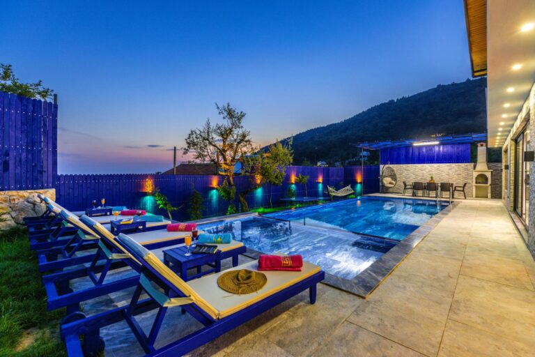Elegant villa with a modern pool and deckchairs, perfect for a relaxing evening getaway.
