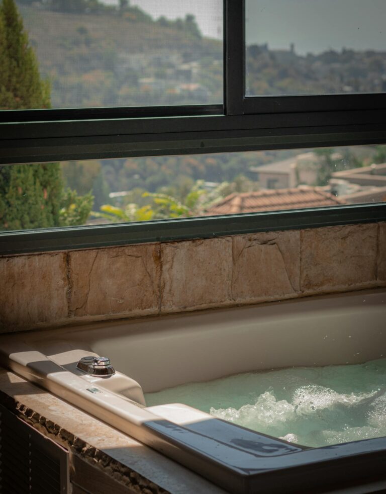 Luxurious indoor bathtub with a scenic view of hills through a large window, perfect for relaxation.